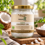 Jar of Natures Root organic coconut oil on a wooden table with coconut flakes